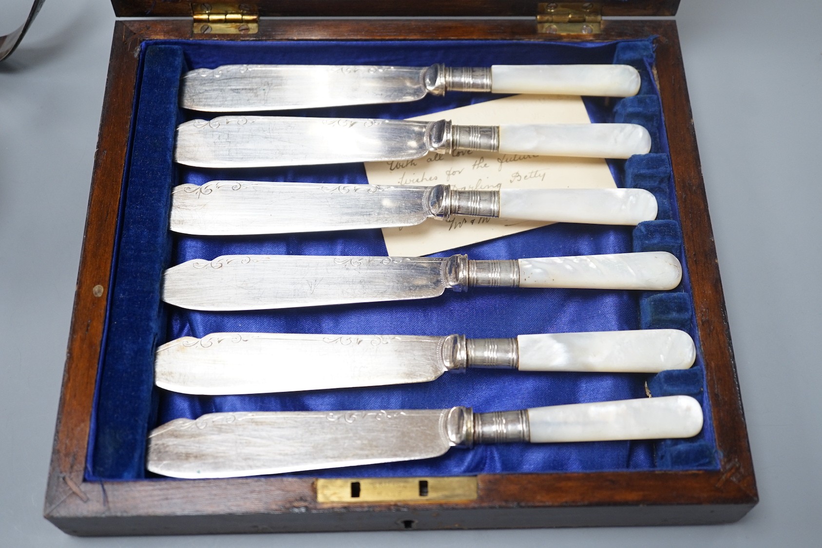 A George V silver octagonal cream jug and sugar bowl, Collingwood & Co, London, 1930, a cased set of six pairs of mother of pearl handled fish eaters and a silver plated claret jug handle.